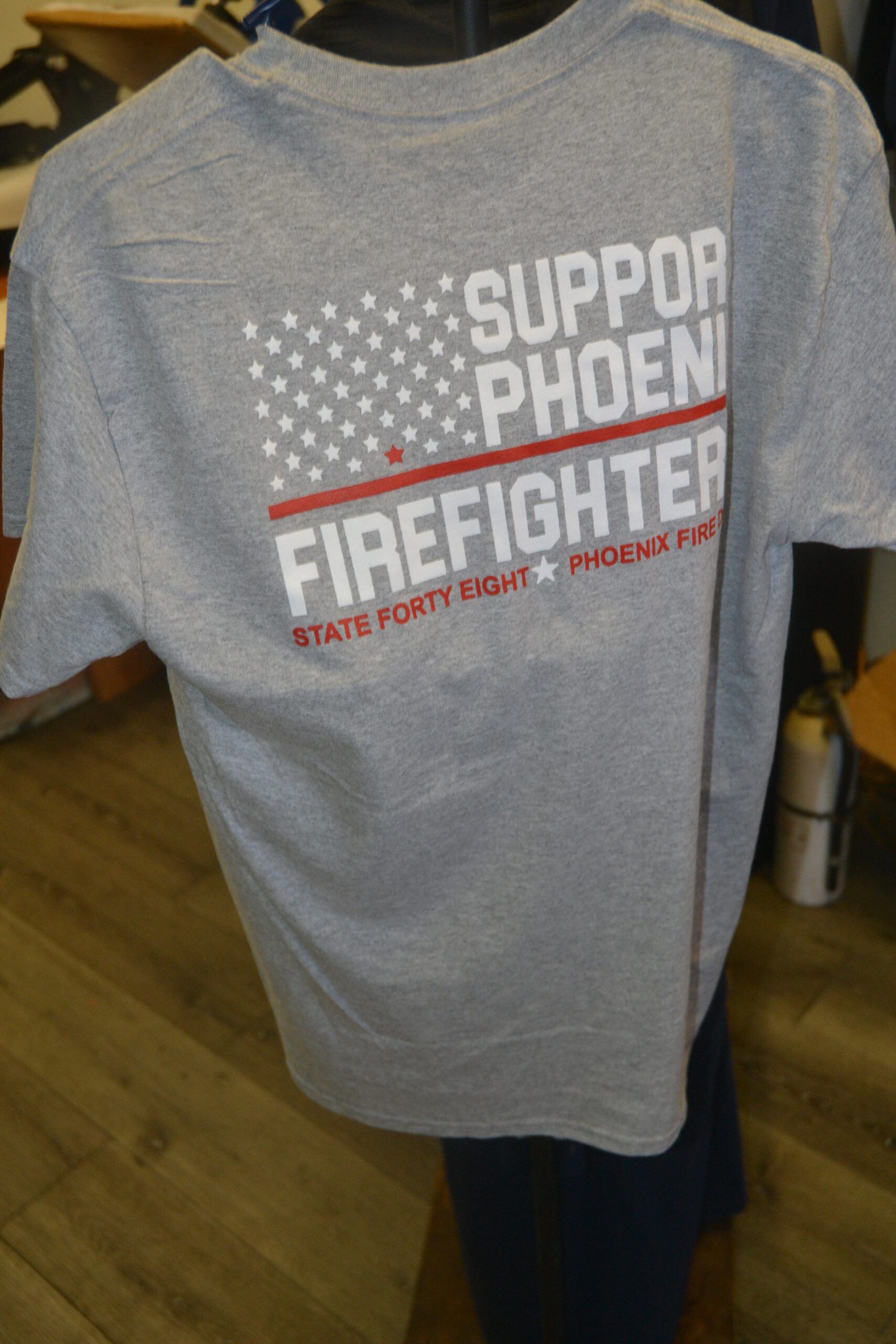 Gray support Phoenix firefighter shirt displayed as a custom apparel example by Phoenix Custom Tees.<br />
