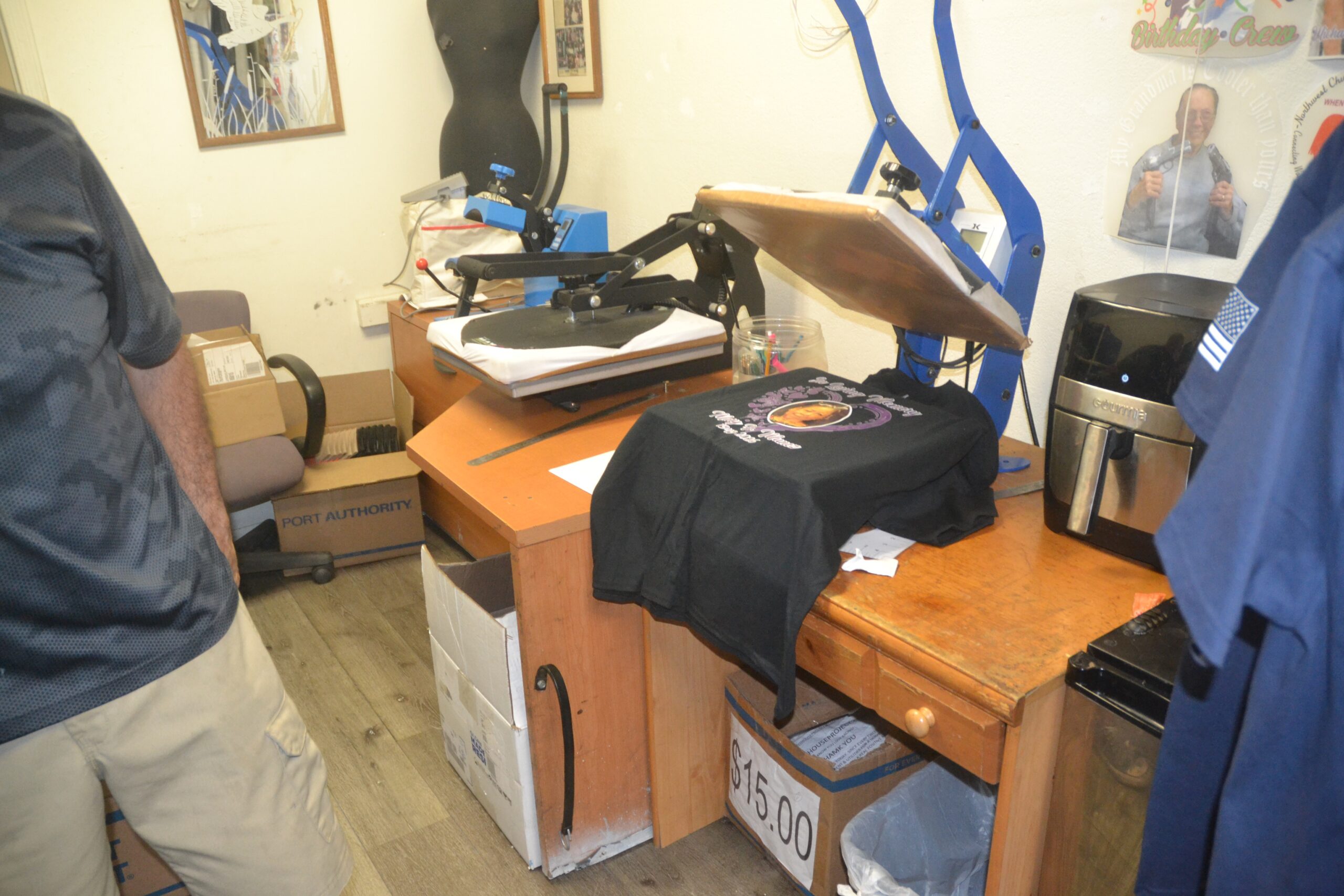 Custom uniform shirt being prepared on a heat press inside Phoenix Custom Tees.